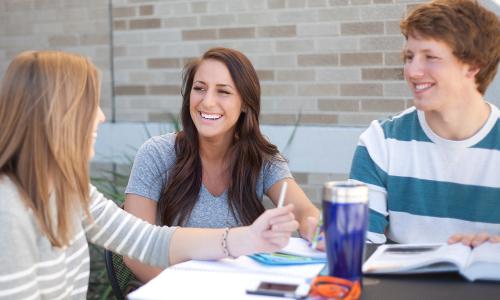 three students sharing a laugh while studying 